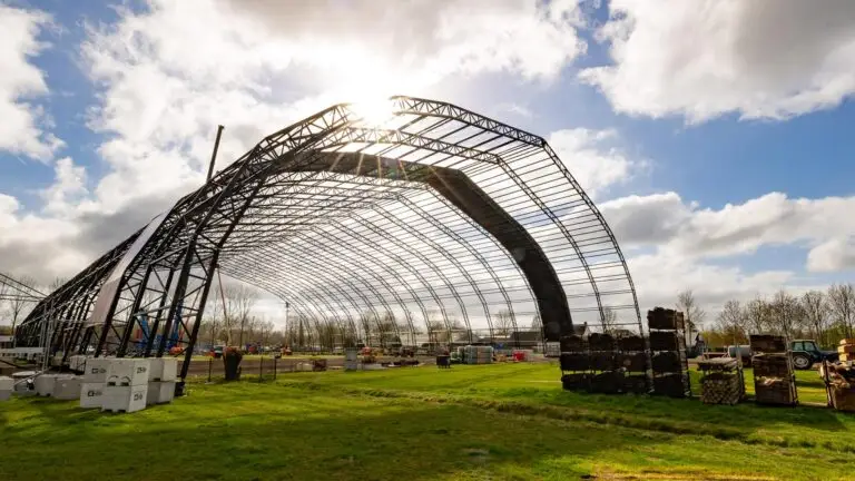 Großes Festivalzeltgestell auf einer Wiese mit Sonne im Hintergrund. Aluminium Zeltprofile von mejo