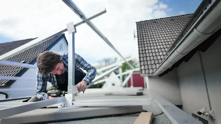 Mann bringt Solarmontageschienen auf dem Carport an