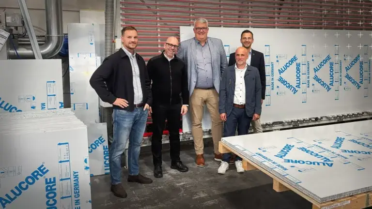 Mitarbeiter von mejo und 3A Composites stehen vor der Säge im mejo Lager