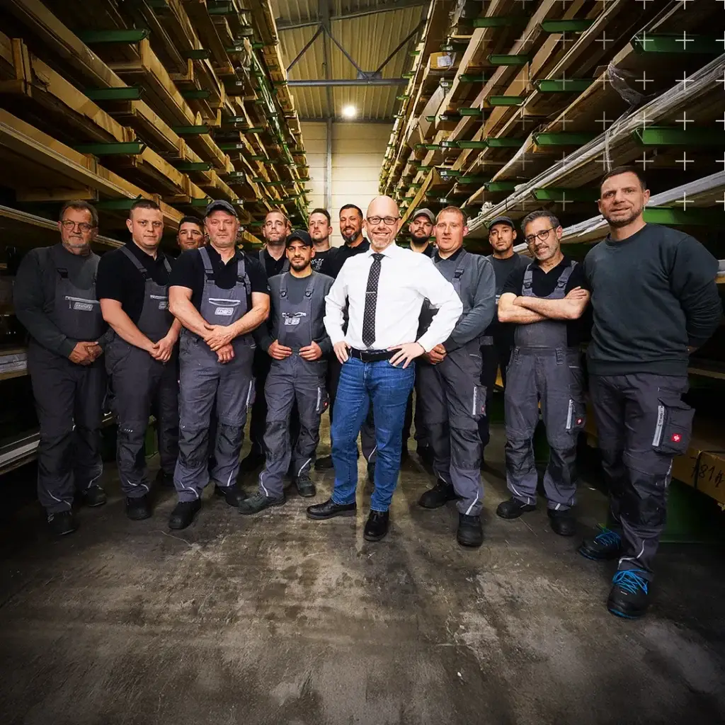 Stephan Josten und ein Team stehen im Lager zwischen Aluminiumprofilen