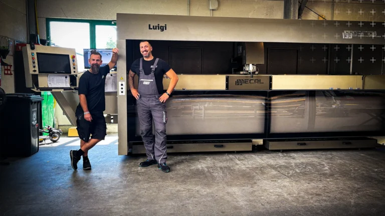 Lagerleiter Paolo Adragna und stellv. Lagerleiter Sebastian Schäfer-Stark stehen vor dem neuen CNC-Stabbearbeitungszentrum bei mejo in Düsseldorf